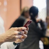 Foto av h&auml;nder som h&aring;ller i en mobiltelefon.